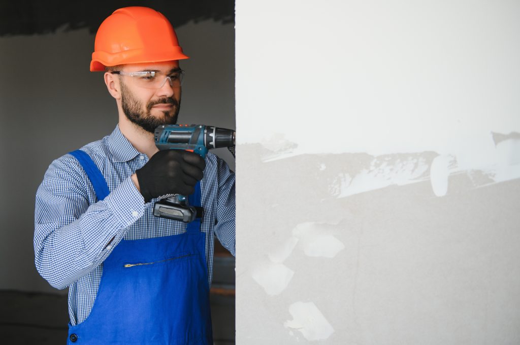 man drywall worker installing plasterboard sheet to wall.
