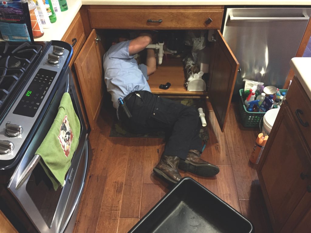 man-working-under-the-kitchen-sink-fixing-the-plum-2022-11-10-09-54-43-utc